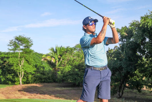 Golfer in action swinging a club on a sunny golf course in Puerto Vallarta, Mexico.