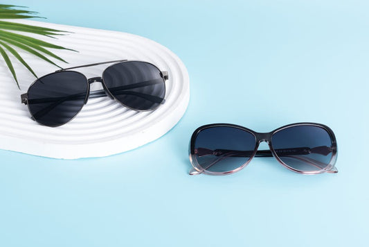 Two pairs of fashionable sunglasses displayed on a minimalist blue background with modern design.