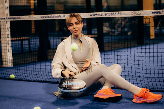 Female player sitting on indoor padel court with gear after match.