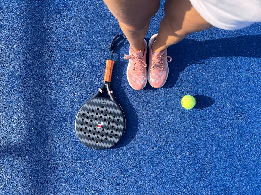 Top view of a padel player with shoes, racket, and ball on a vibrant blue court.