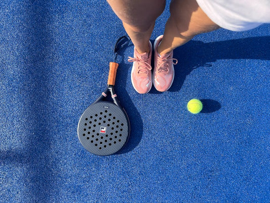 Top view of a padel player with shoes, racket, and ball on a vibrant blue court.