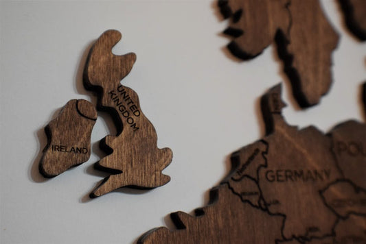 Close-up of wooden puzzle pieces shaped like the UK and Ireland on a white background.