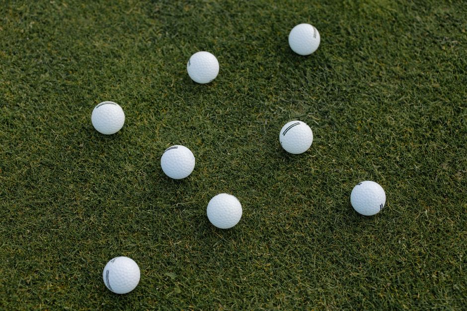 A visually appealing composition of scattered white golf balls on a lush green grass field.
