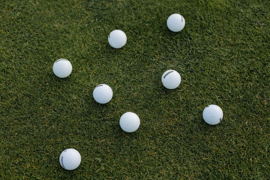 A visually appealing composition of scattered white golf balls on a lush green grass field.
