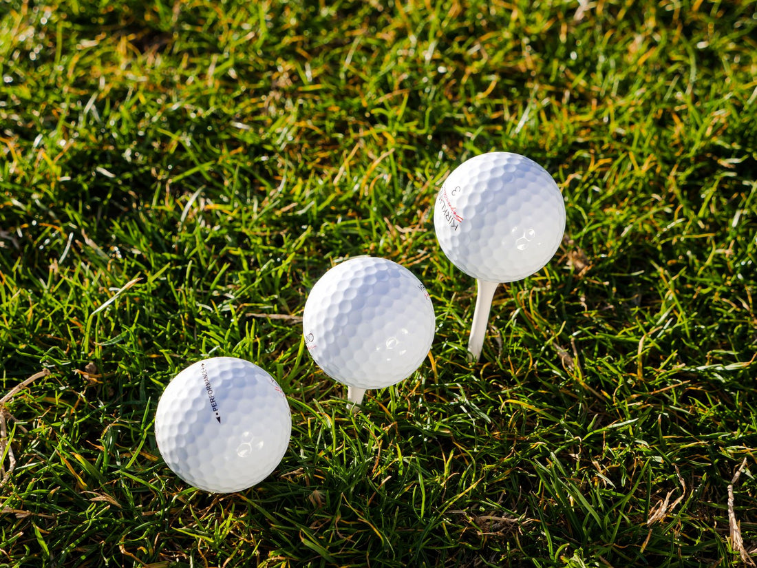 Three golf balls positioned on lush green grass with one on a tee, perfect for sports enthusiasts.